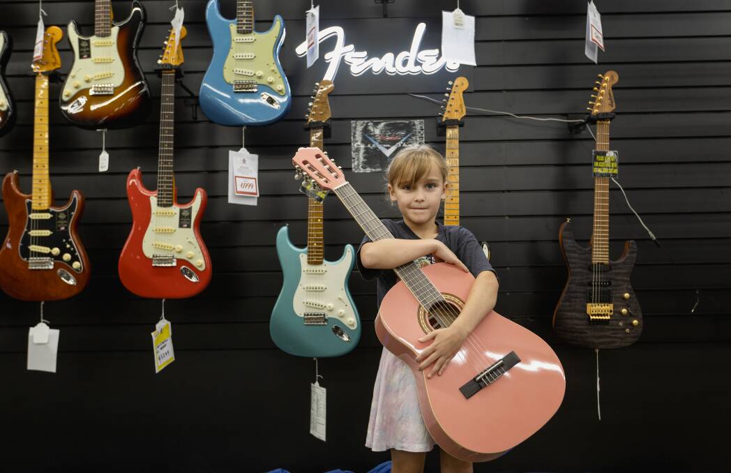 Alexis Lean clutches her first guitar at the Musos Corner May the Fourth sale on Saturday. Pink is her favourite colour, she said, and she has been learning to play with her dad. Picture by Marina Neil