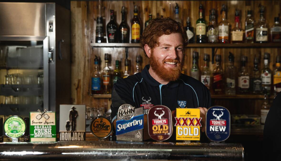 Alex Mackay pulling beers at Adamstown Bowling Club where he started working six months ago. Picture by Marina Neil
