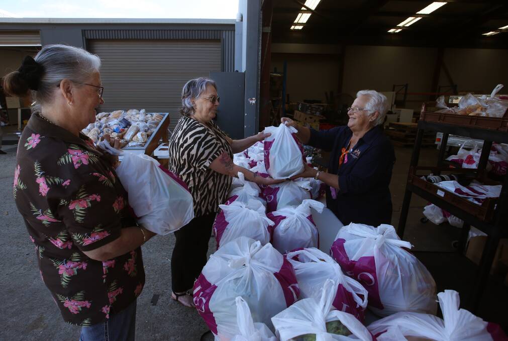 Survivor's R Us volunteer Sandra Eaves hands out food packs to sisters Coleen Cleary and Glenda Laird of Speers Point. Frontline agencies are battling to find enough food for those going hungry due to the rising cost of living and lack of affordable housing. Picture by Simone De Peak