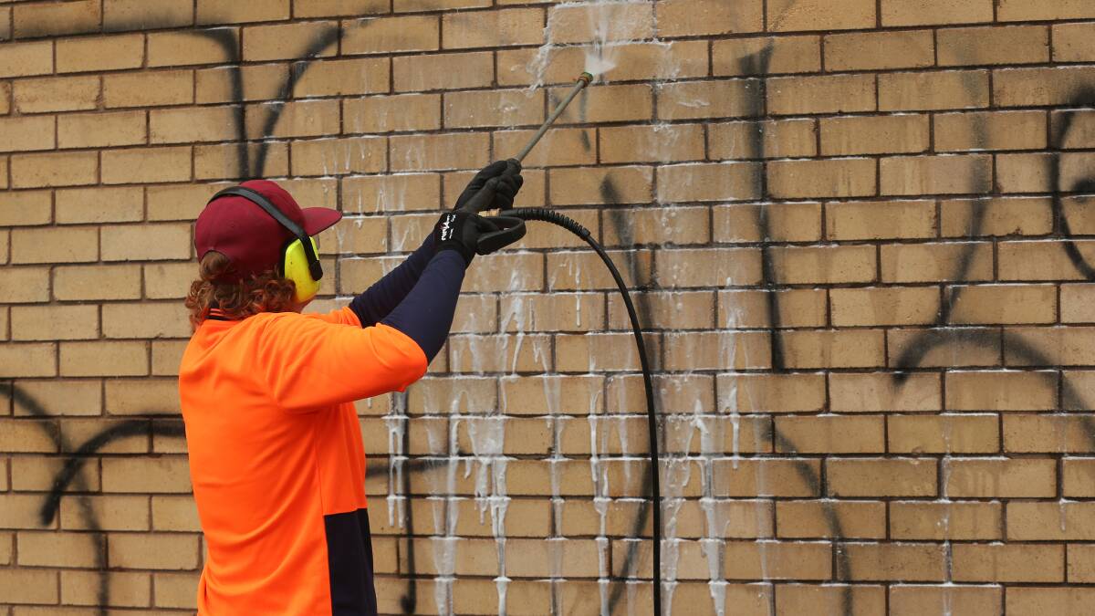 Cleaning up: Graffiti removal in action at Wellfit Personal Training as part of a partnership between Newcastle City and Youth Justice NSW. Picture: Simone De Peak