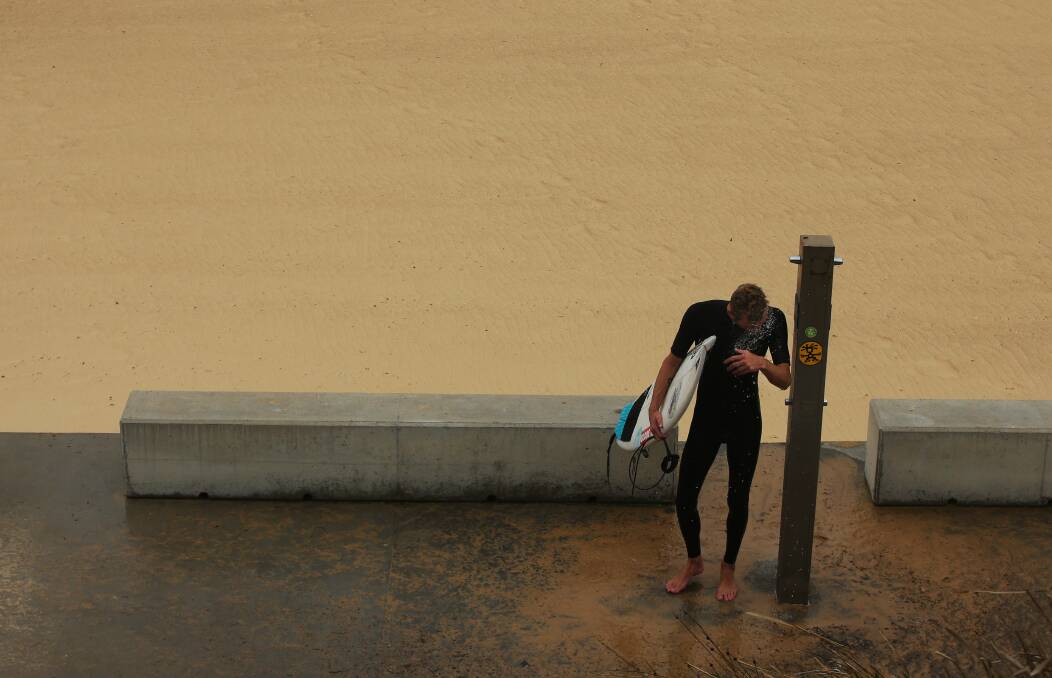A surfer at a virtually deserted Merewether beach on Monday. Picture by Simone De Peak