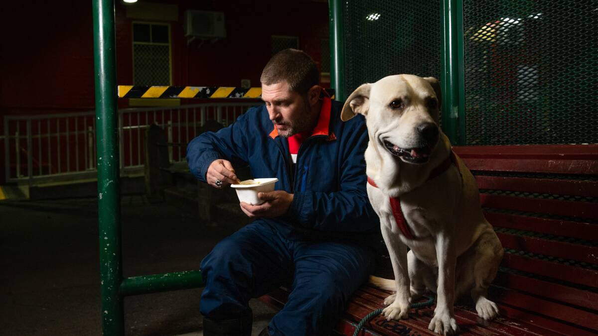 Nourishment: Nicholas Harrison savours a meal from Food Not Bombs at Hamilton, with his dog Banjo. Picture: Marina Neil