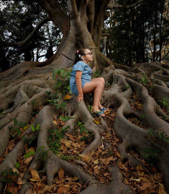 Growing up: Abbi Keating, age 8, sitting on the roots of a fig tree in Pacific Park. Picture: Max Mason-Hubers