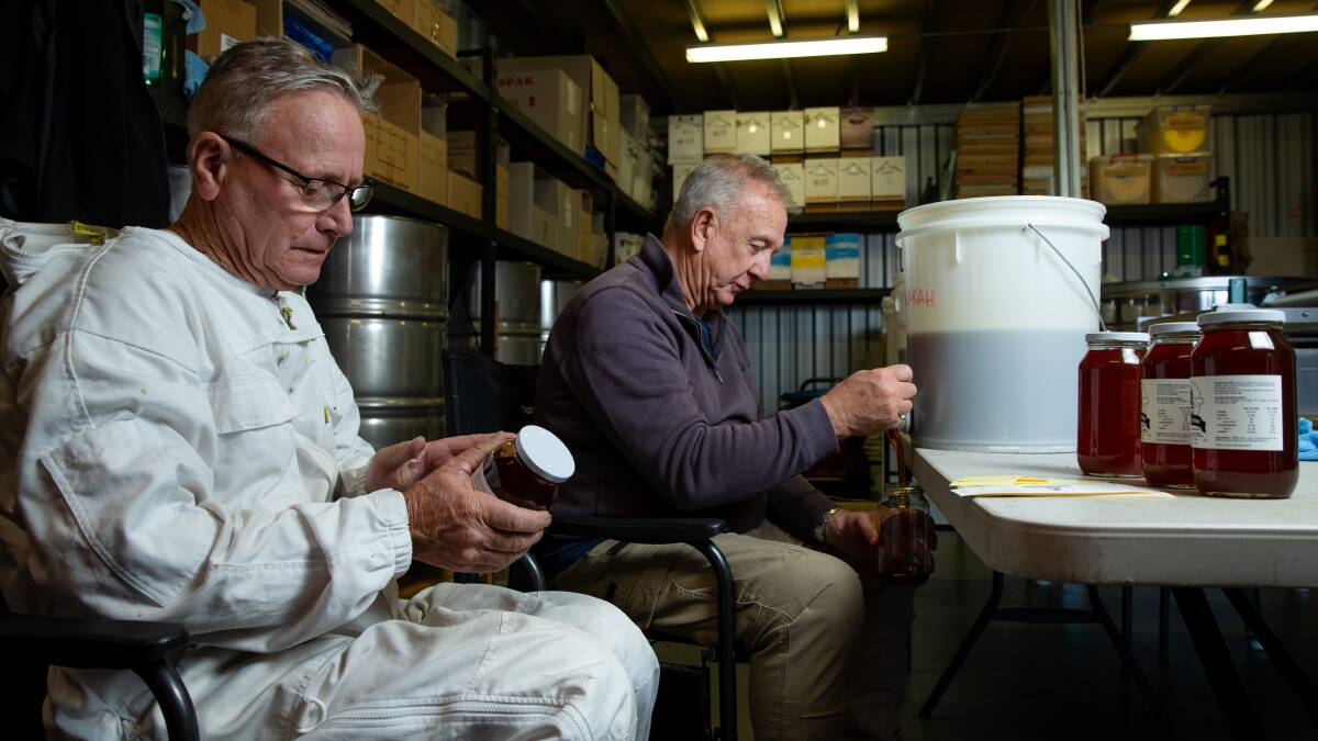 Taking care of business: Tony Hendriks, left, and Russell Smith, bottling and labelling their 2 Pops Honey product from their Caves Beach facility. Picture: Marina Neil