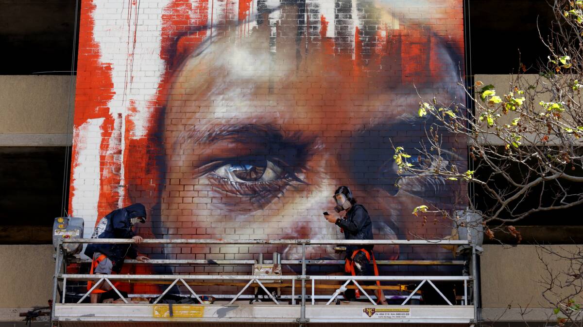 Change of scenery: Adnate (right) painting a work on a parking garage on Bolton Street in Newcastle in 2015. Picture: Simone De Peak