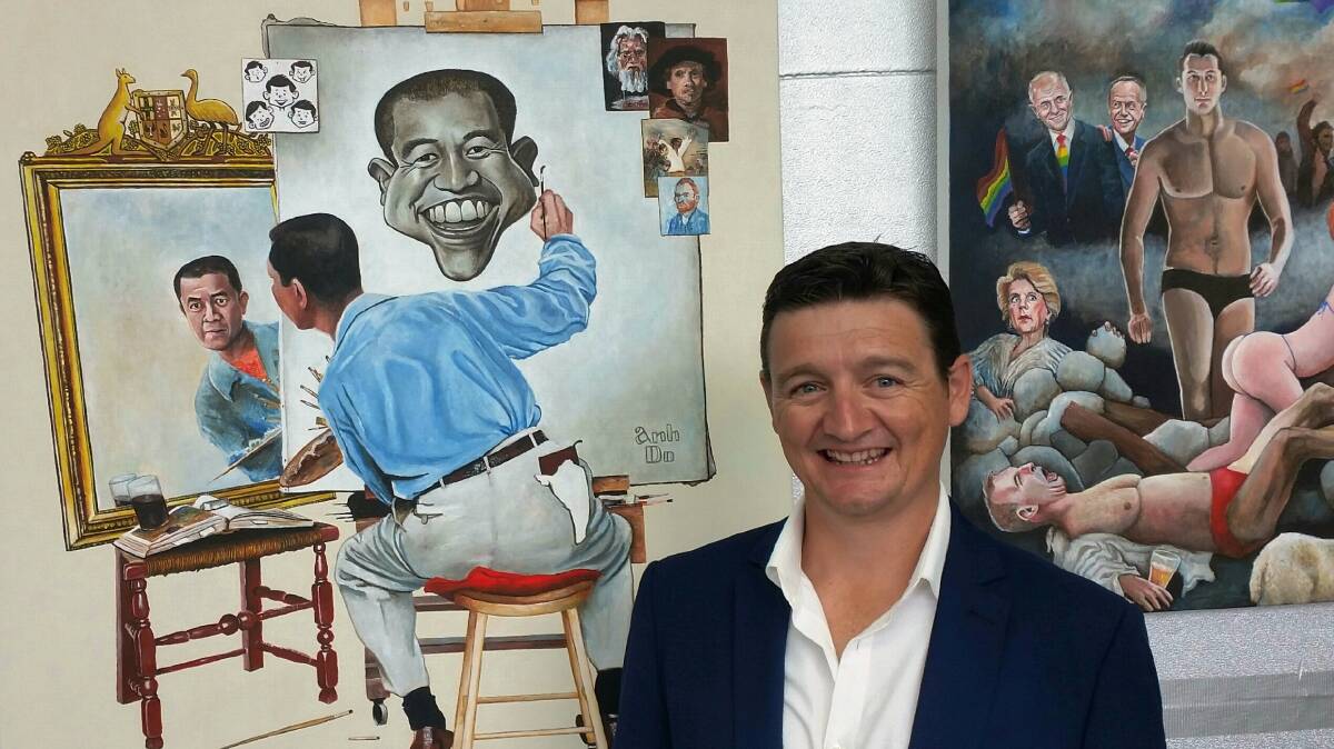 Grinning winner: Artist James Brennan with his 2018 Bald Archy work. The partially-visible artwork on the right was another Brennan work in the competition, depicting several politicians. 