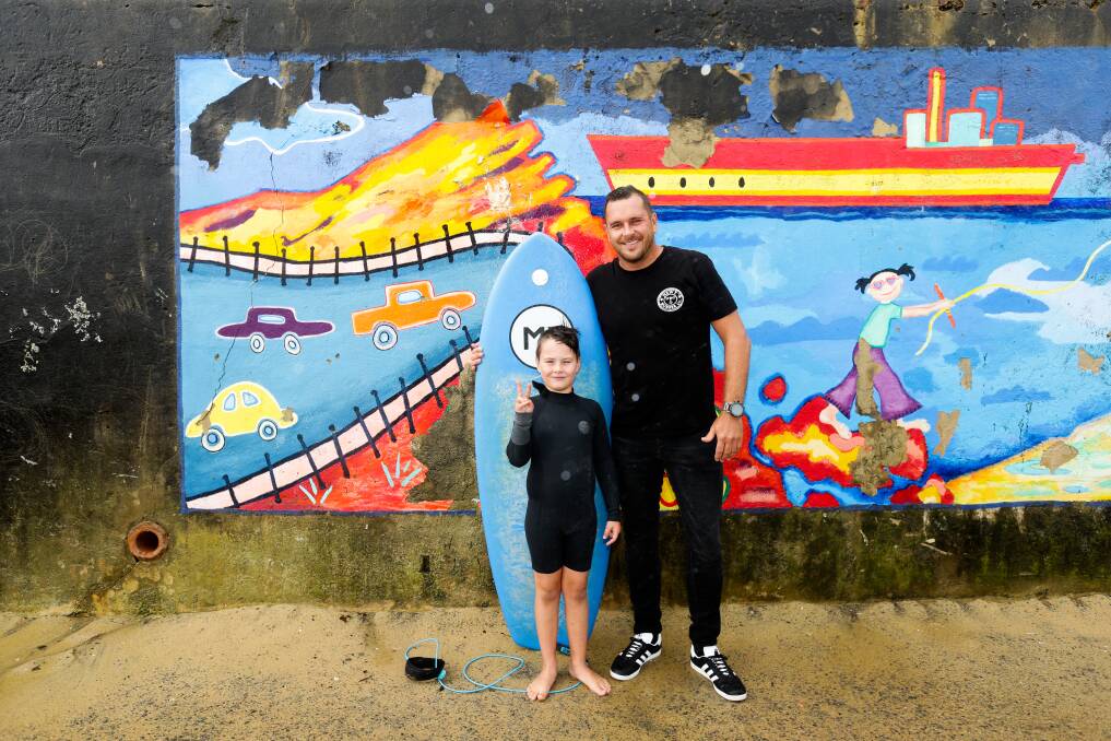 SurFebruary: Xavier Neil, 8, with his dad Ben, at Bar Beach. Xavier is surfing to raise money to fight cancer. Picture: Jonathan Carroll