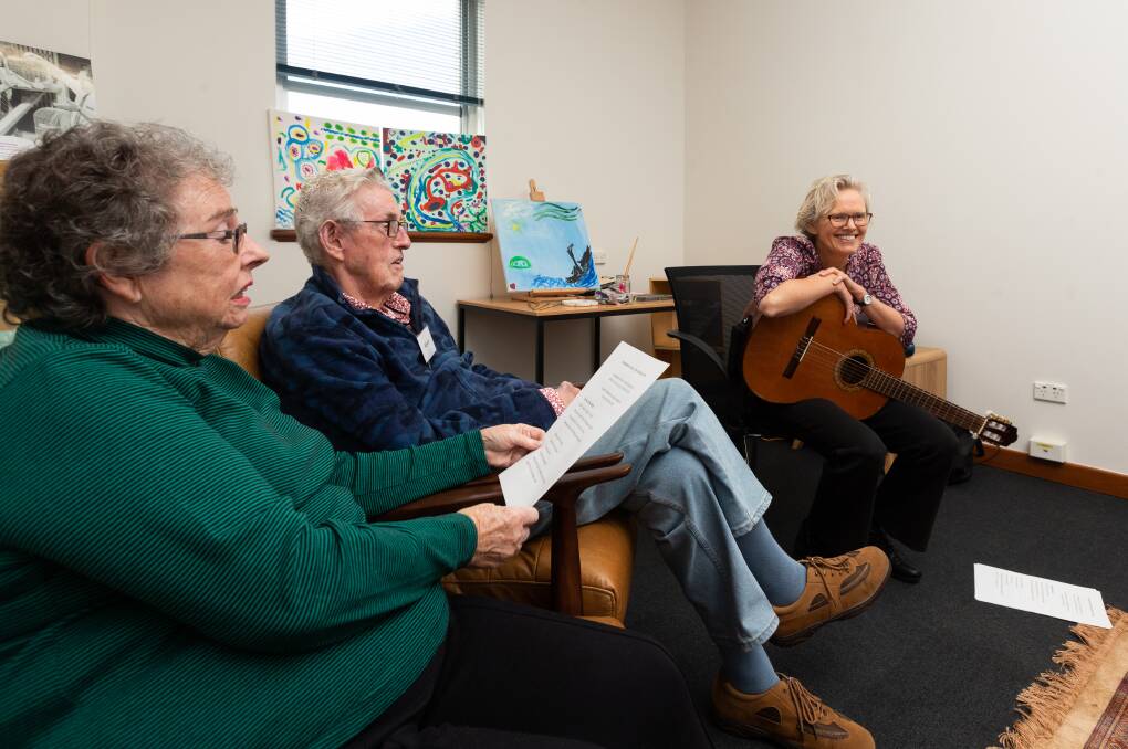Music therapist Susan Ashley-Brown, with the guitar, with Keven and Catherine Claydon during a Memory Room moment at Newcastle Library. Picture by Jonathan Carroll