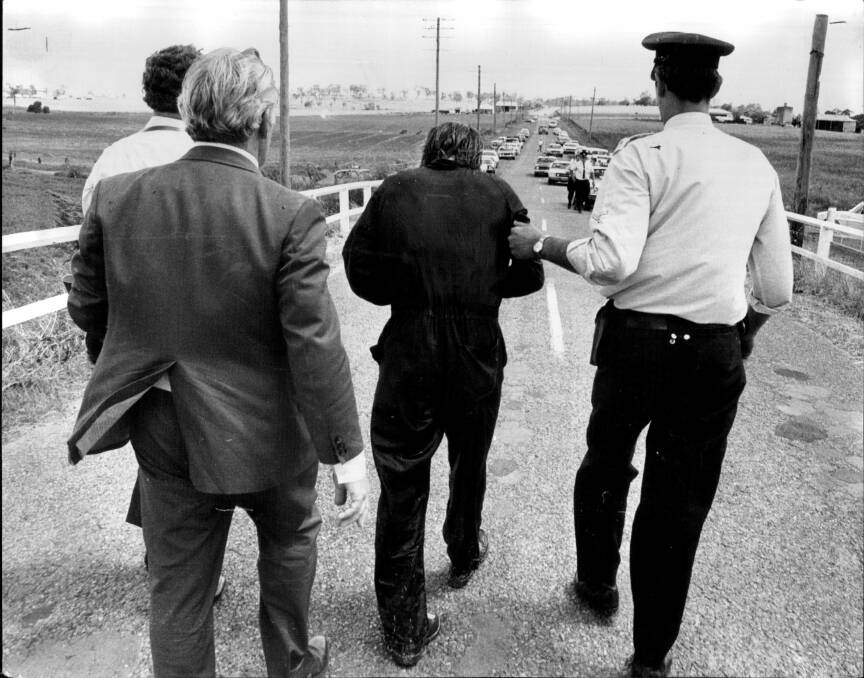 Historic day: Kevin Crump, stooped and shivering, is led away after his capture. 