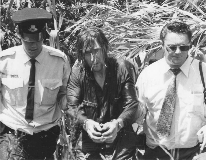 CAPTURED: Kevin Crump, cold and wet with teeth chattering, is flanked by police after being arrested at Dudmore Bridge, near Woodville in November 1973.