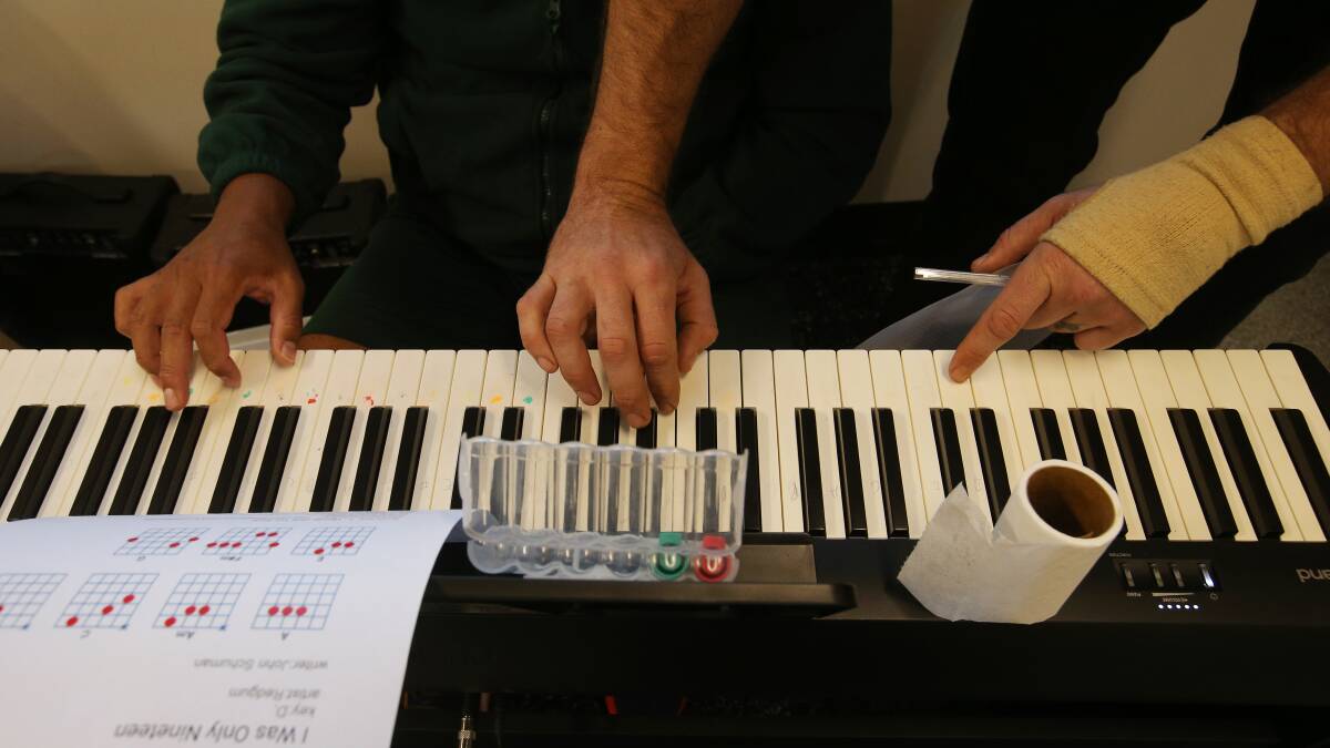 William Crighton and an inmate at Hunter Correctional Centre practise notes on an organ earlier this year. Picture by Simone De Peak