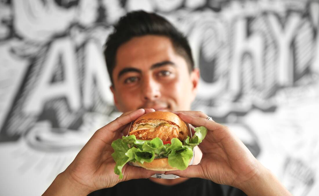 Handful: Shaquille McCabe wraps his hands around a Marty McFly burger at Rascal on King Street in Newcastle. Picture: Marina Neil