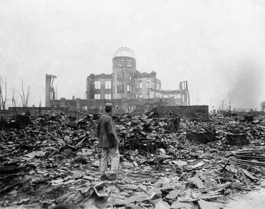 Devastation: A journalist stands on rubble near the shell of the only building left standing near the epicentre of the atomic bomb that hit Hiroshima.  