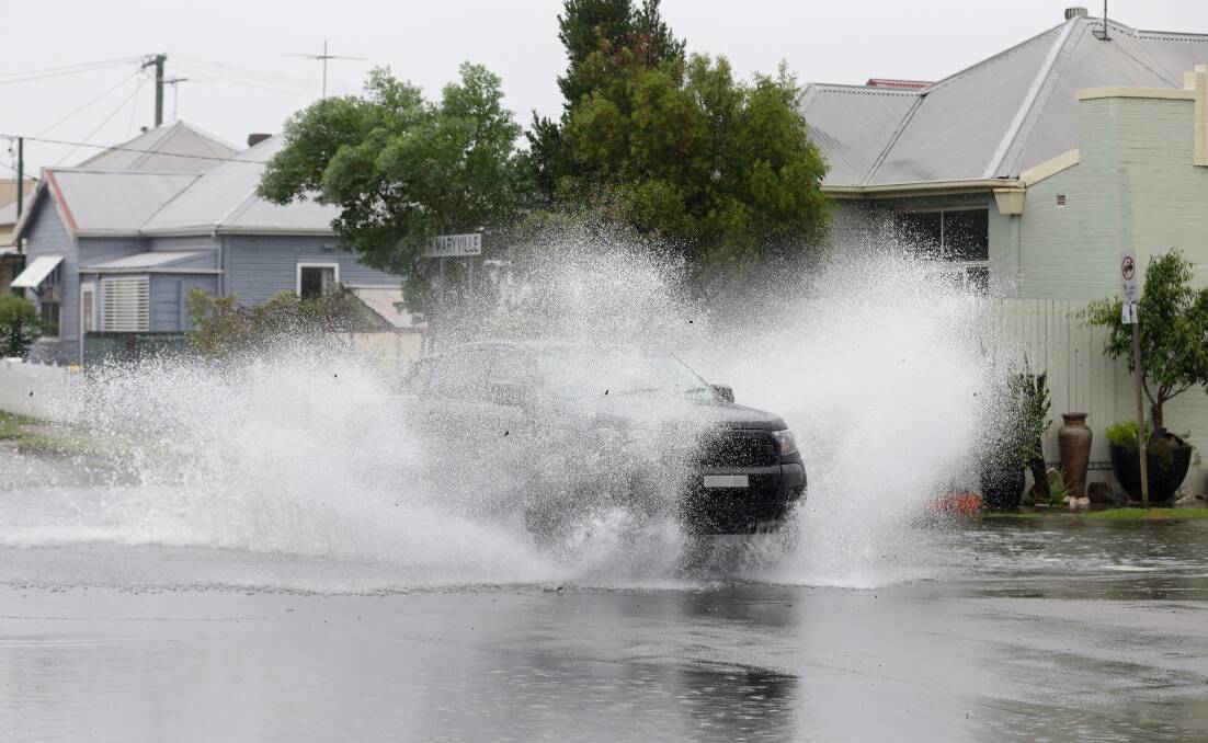 A four-wheel drive going through a flooded street at Maryville. The SES has urged motorists not to drive through floodwater. Picture: Jonathan Carroll 