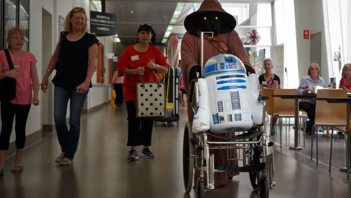 Glen Fredericks, dressed as a jawa from Star Wars, pushes an inflatable R2-D2 robot in a wheelchair at John Hunter Children's Hospital to spread Christmas cheer.
 