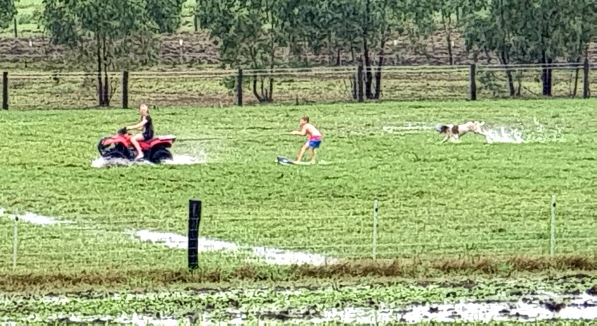 Whoopee: Kids and a dog have some fun in the rain on a flooded property at South Maitland. Picture: Col Maybury 