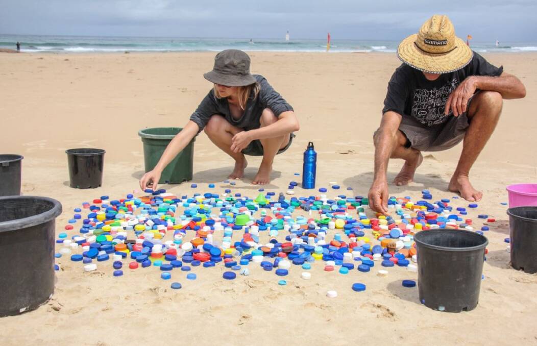 Polluted: Plastic accounts for 84 per cent of all rubbish found on Australian beaches. Lindsay and Sophie Brown on Birubi Beach in Port Stephens in 2017, with thousands of plastic bottle caps collected over a year. Picture: Sophie Brown 