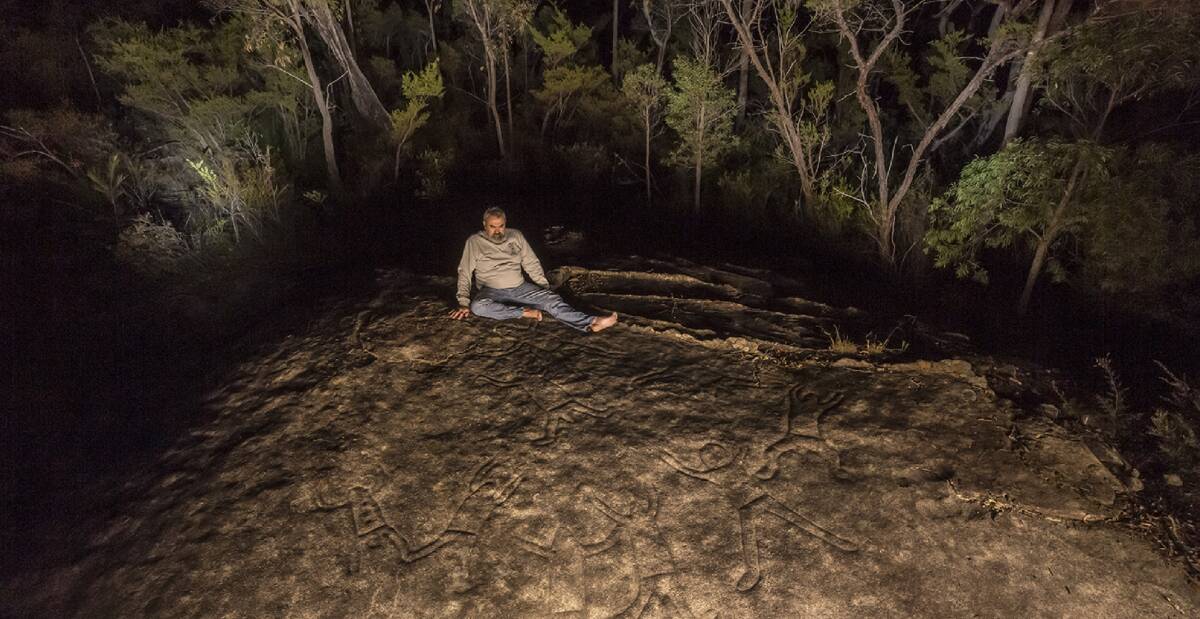 Significant: Aboriginal elder Warren Taggart on a rock with Aboriginal engravings in Yengo National Park. Pictures: Allan Chawner 