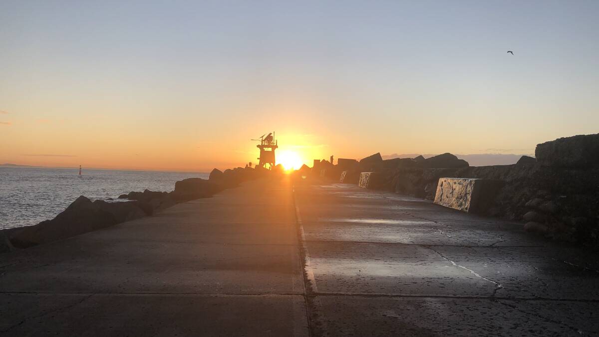 Sun Worship: The sunrise above Nobbys breakwall could have some kind of pagan meaning ... or not. Picture: Ross Kerridge 