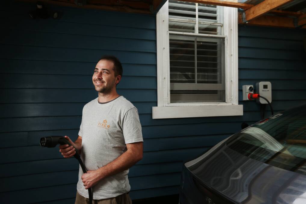 Ryan Wilcox installs and sells chargers for electric vehicles. He's shown here with a charger and Tesla in Hamilton. Picture by Simone De Peak 