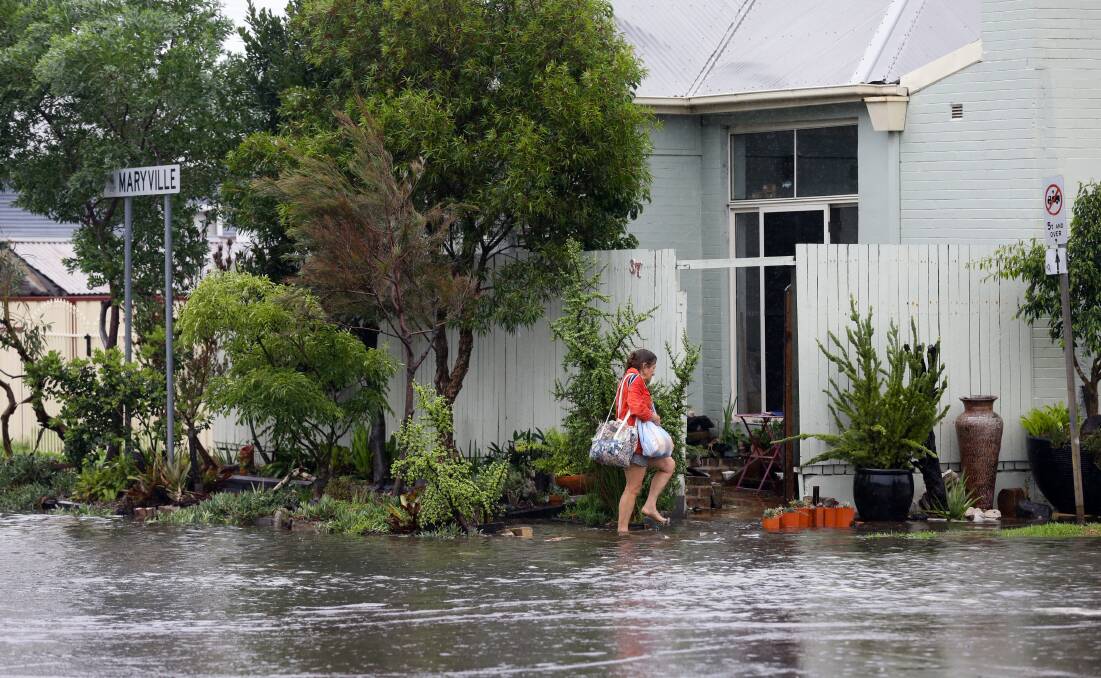 Wet Weather: Sue Russell enters her Maryville property in her flooded street. Picture: Jonathan Carroll 