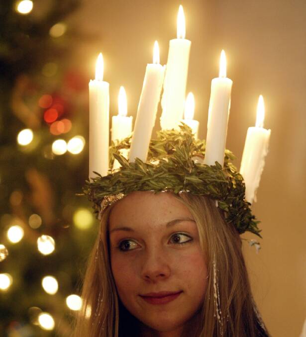 Light Dawns: A Swedish girl wearing a wreath of candles to mark St Lucia Day.   