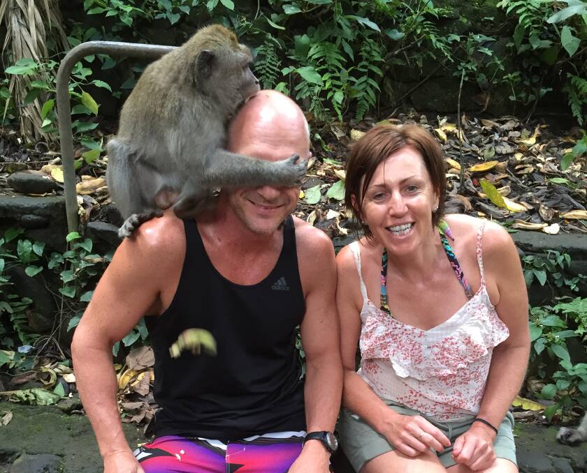 Monkey Business: A monkey bites Anthony Wallace on the head as he sits next to girlfriend Libby McManus at Ubud Monkey Forest in Bali. 