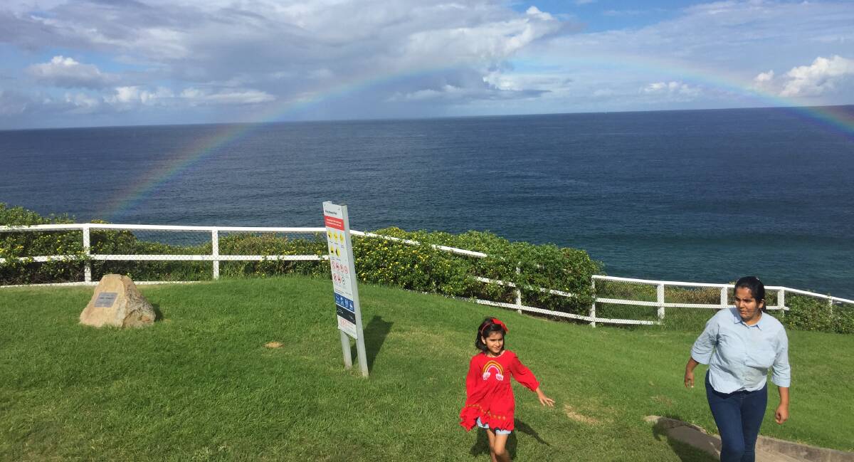 ANOTHER SIGN: If the extraordinary rainbow isn't an omen enough, have a look at the pattern on the girl in the red dress. It's a rainbow . . . Feels like it's time to get down to Merewether, if you haven't already. Picture: Ian Kirkwood