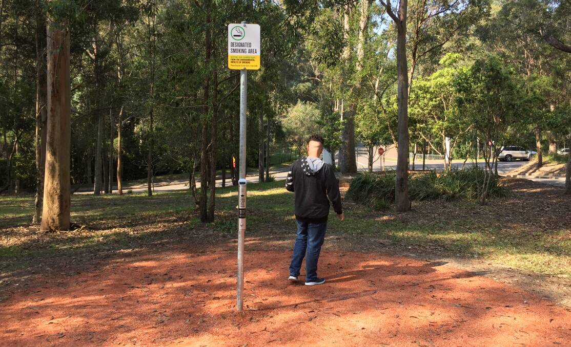 A student takes a quick break between lectures at a designated smoking area after the University of Newcastle backed down on its campus smoking ban.
