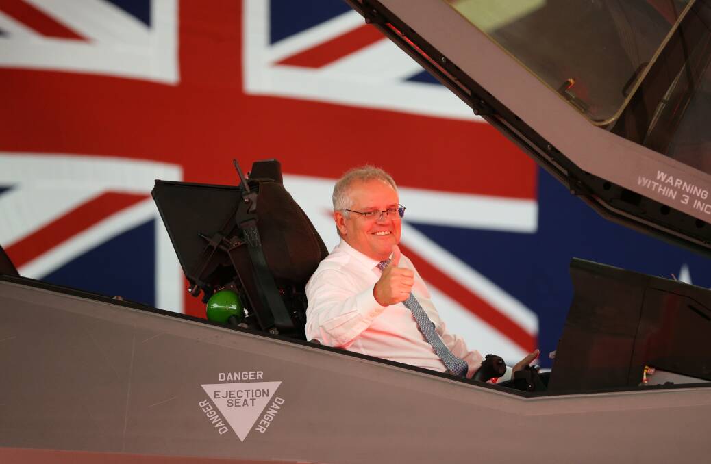 SYMBOLISM: Politicians have always been attracted to the photo opportunities presented by military hardware. The giant Australian flag that covered a large part of one wall of the BAE Systems hangar is presumably not part of the usual decoration. While that was the backdrop the government wanted, it was difficult not to focus on the 'Danger Ejection Seat' sign under the PM's elbow. Picture: Jonathan Carroll