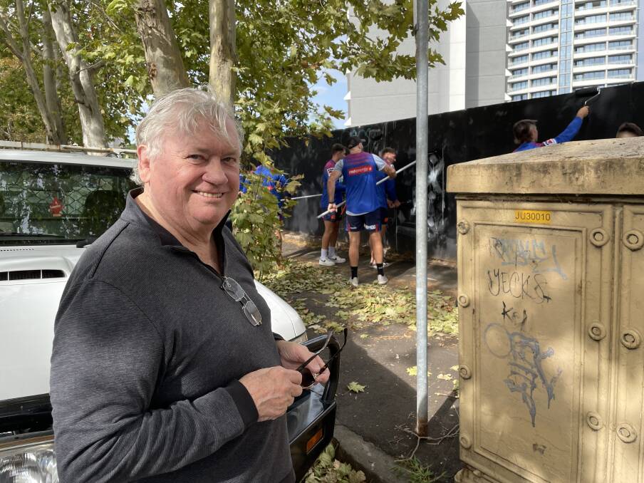 COMMUNITY PRIDE: Businessman and former Newcastle lord mayor Jeff McCloy in Steel Street this morning as the Knights players behind him put the finishing touches to a newly clean hoarding. Picture: Ian Kirkwood