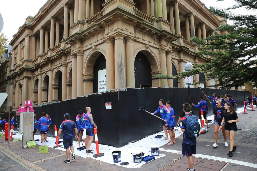 PAINT IT BLACK: Newcastle Knights first-graders rip into the hoarding in front of the old Newcastle post office soon after 8am today. Picture: Peter Lorimer