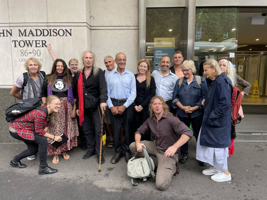 Paul Burton, with cane, and Andrew Katelaris next to him, with supporters outside Sydney District Court yesterday. Picture by Ian Kirkwood