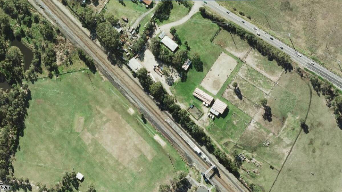 OVERVIEW: The railway line, with Metford station and its single overpass, at the bottom centre of the image. The Boyle family land sits between the rail line and Raymond Terrace Road, with vehicles, to the top right. Picture: Six Maps, NSW Government