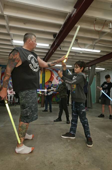 Luke Boynton teaching Isaac Coppard, 10, how to lightsaber battle. Picture: Simone De Peak