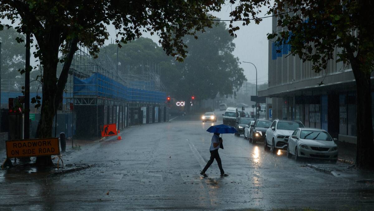A mid morning downpour in Newcastle had rivers running down the roads and people hiding from the rain. National Park Street. Picture by Max Mason-Hubers