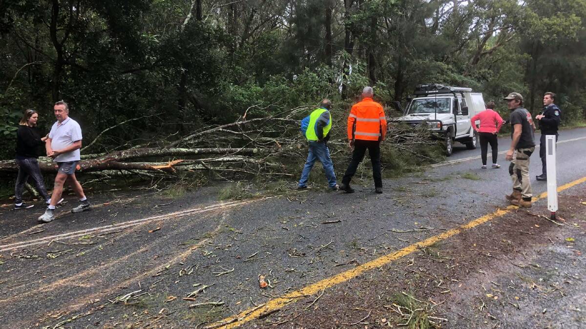 HELP: Locals help to move debris off the road at Hawks Nest just past the Singing Bridge. Picture: Beth Mitchell 