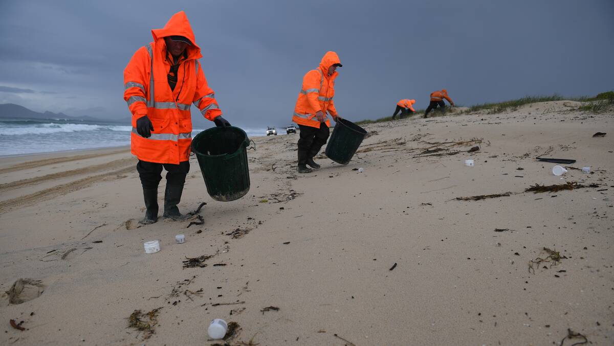 Clean up contractors are seen clearing debris from the beach at Hawks Nest near Port Stephens, north of Newcastle on Tuesday. Picture: AAP Image/Dan Himbrechts