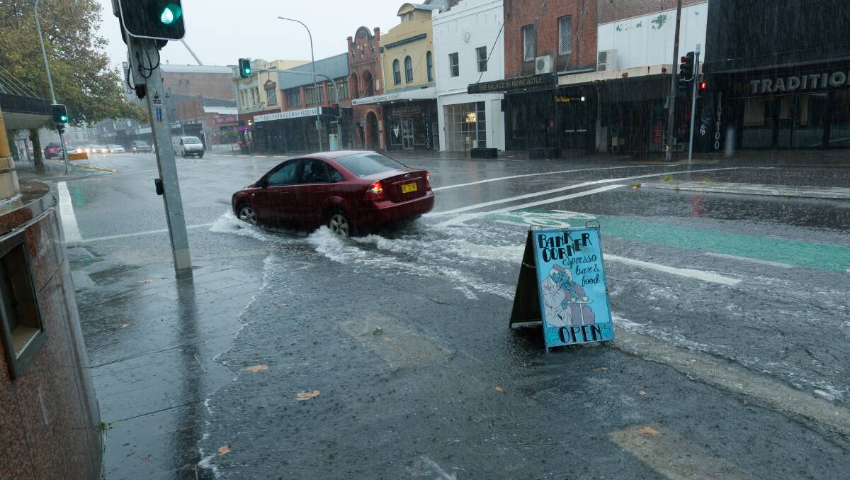A mid morning downpour in Newcastle, as a car drives through a deep puddle at the intersection of Hunter St and Bellevue St. Picture by Max Mason-Hubers 