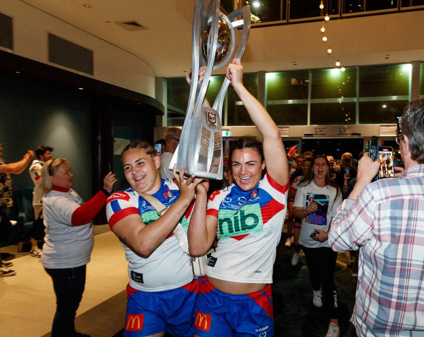 Caitlan Johnston and Mille Boyle carry the NRLW premiership trophy into NEX Club in Newcastle after taking grand final victory over Parramatta in October. Picture by Max Mason-Hubers