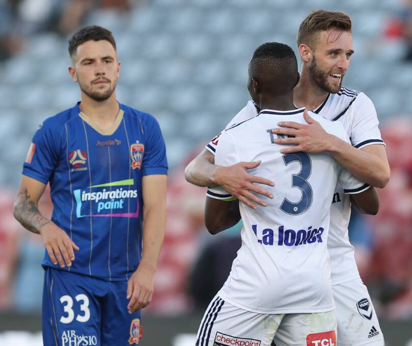 ONE THAT GOT AWAY: Newcastle's Apostolos Stamatelopoulos is a picture of disappointment as Melbourne Victory players celebrate their win at McDonald Jones Stadium on Saturday. Picture: Ashley Feder