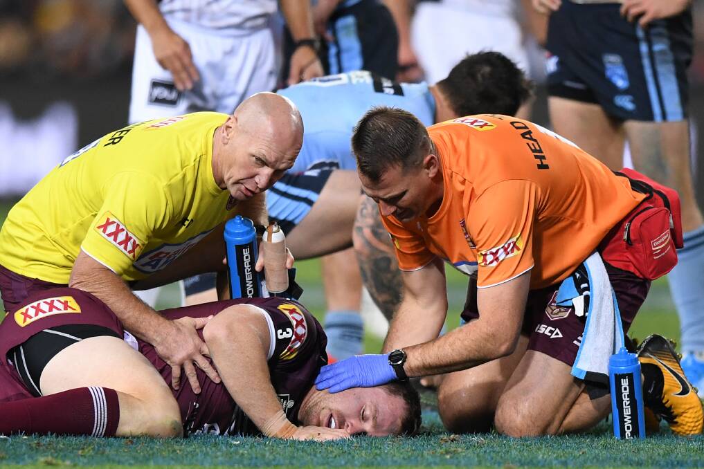 DOWN FOR THE COUNT: Michael Morgan receives treatment in Origin III before being helped from the field. It was his second concussion in as many games. Picture: AAP