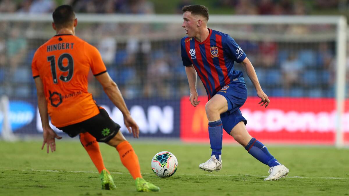 ON THE BALL: Bobby Burns looks to go past Jack Hingert in the Jets 1-all draw with Brisbane Roar at McDonald Jones Stadium on Saturday night. The Northern Ireland left back put in a solid shift in his starting debut for the Jets. Picture: Getty Images