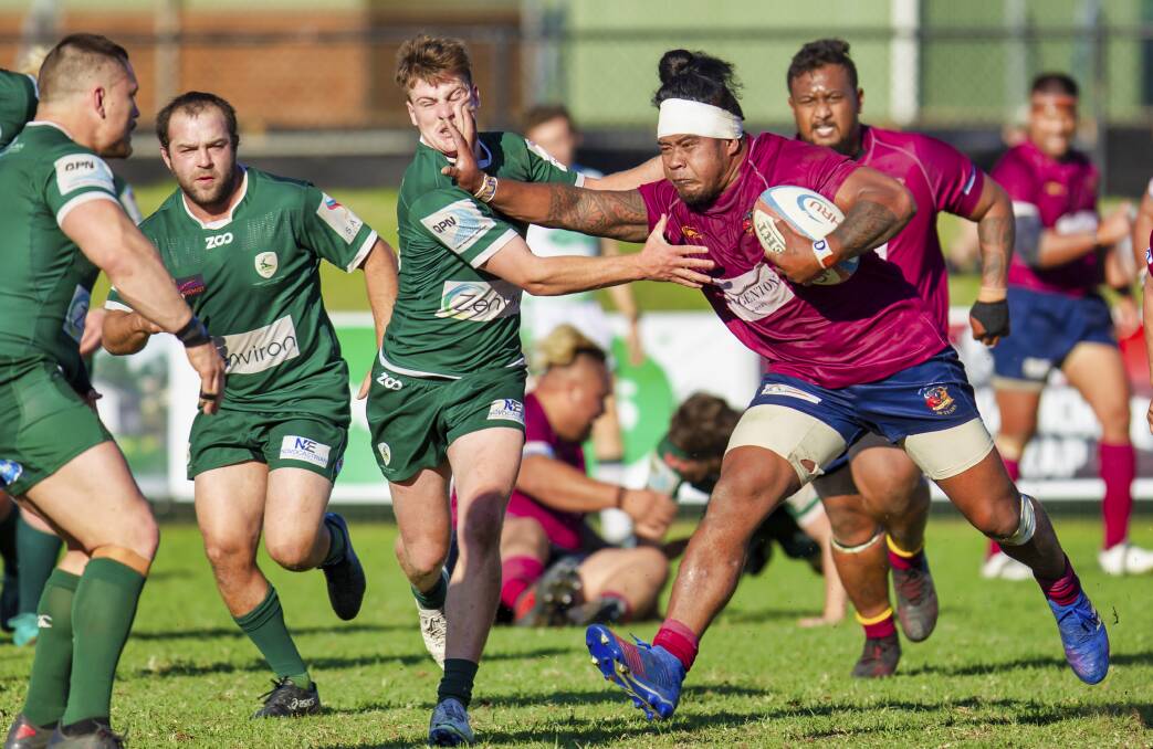 IN YOUR FACE: Lake Macquarie breakaway Sapati Peniata palms off an attempted tackle by Merewether fly-half Toby Wait. Picture: Stewart Hazell