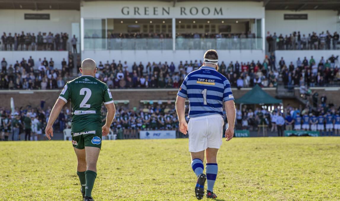COMMUNITY SPIRIT: Merewether captain Billy Dunn and Wanderers opposite Dave Waller cross the field after laying ANZAC Day wreaths at Townson Oval. The Greens beat the Two Blues 30-19 in front of a crowd of more than 3000. Picture: Stewart Hazell.