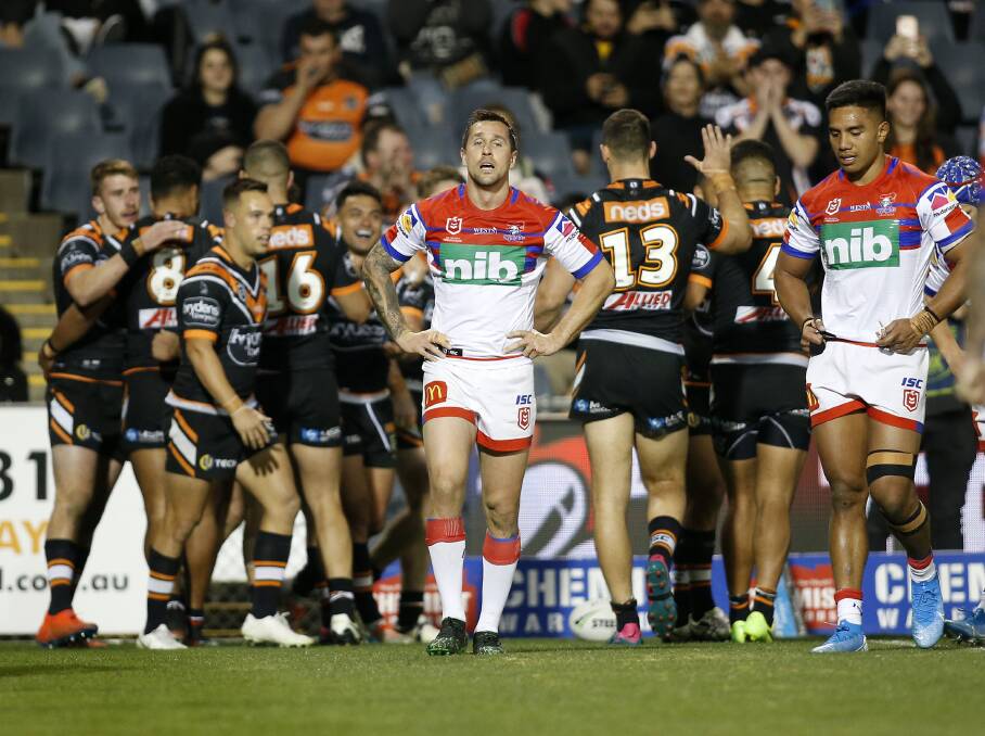 DEJECTED: Knights captain Mitchell Pearce (centre) shows his disappointment as the Tigers celebrate a try in their 46-4 win at Campbelltown Sportsground. The heavy defeat was the catalyst for Nathan Brown's decision to part ways with the club on Tuesday. Picture: AAP 