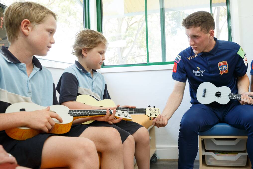 IN TUNE: Jets fullback Bobby Burns helping brothers Max and Eli with a ukulele lesson during a visit to Ronald McDonald House on Wednesday. Picture: Max Mason-Hubers 
