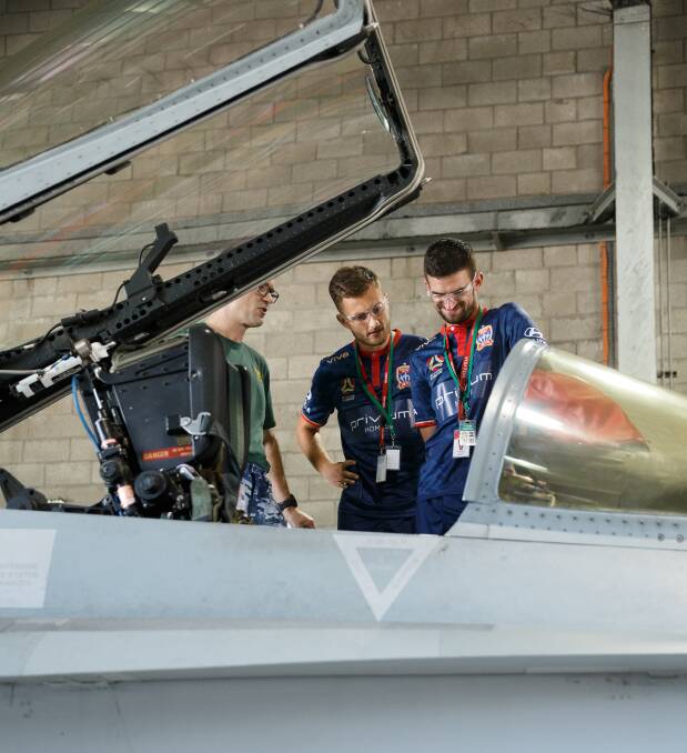 INSPECTION: Squadron Leader Scott Schultz shows Steven Ugarkovic and Kaine Sheppard the cockpit of an F/A-18 Hornet fighter jet at the Williamtown RAAF base. Picture: Max Mason-Hubers