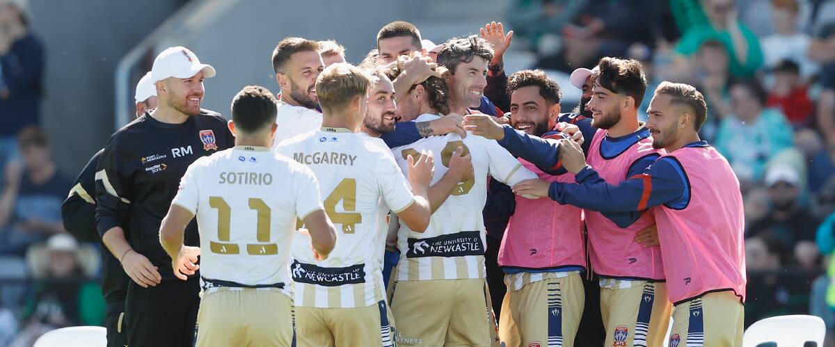 Daniel Stynes, centre, embraces teammate Jason Hoffman as the Jets celebrate his super strike on Sunday against Western United at Mars Stadium in Ballarat. Picture by Rob Prezioso, AAP
