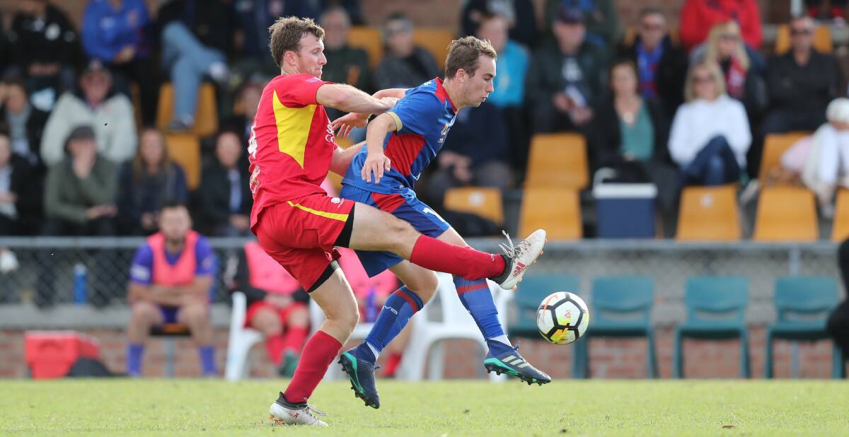 BATTLEFIELD: Newcastle Jets young gun Angus Thurgate in action for the youth team against Broadmeadow's Jon Griffiths last season in the NNSW NPL. Picture: Jonathan Carroll